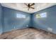 An empty bedroom with beautiful wood-look flooring, blue walls, ceiling fan, and windows at 7541 Julian St, Westminster, CO 80030
