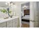 Bathroom with double sink vanity leading into main bedroom with wood accent wall and soft colors at 6558 Kenzie Cir, Castle Pines, CO 80108
