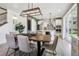 Open dining room with modern light fixture, wood floors, and view into the bright, white kitchen at 6558 Kenzie Cir, Castle Pines, CO 80108