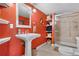 Bathroom featuring an orange wall, bright light, pedestal sink, and a stylish glass-door shower at 1621 Beacon Hill Dr, Highlands Ranch, CO 80126