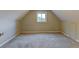 Spacious attic featuring neutral colored walls and carpet, with a single window at 1707 W 39Th Ave, Denver, CO 80211