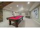 Basement with brick features, plush sofas, dark coffee table and pool table in next room at 15258 W 75Th Pl, Arvada, CO 80007