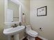 Classic half bath with a pedestal sink, framed mirror, and hardwood floors creating an elegant and functional space at 15258 W 75Th Pl, Arvada, CO 80007