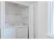 Well-lit laundry room with washer, dryer, and shelving for convenient storage at 2260 Lilly Dr, Thornton, CO 80229