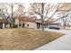 Exterior home view with two-car garage, brick facade, mature trees, and landscaping at 7250 Eastmoor Dr # 105, Denver, CO 80237