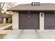 Garage exterior with a brown door, brick facade, and lighting fixture at 7250 Eastmoor Dr # 105, Denver, CO 80237