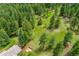 Expansive aerial view showcasing the property's lush green meadow nestled within a dense, verdant forest at 28065 Camel Heights Cir, Evergreen, CO 80439