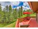 Inviting back deck area with a dining table set and relaxing lounge chairs surrounded by lush greenery at 28065 Camel Heights Cir, Evergreen, CO 80439