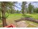 An image showing a backyard with wooden retaining wall, lush green grass, and towering trees at 28065 Camel Heights Cir, Evergreen, CO 80439
