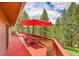 Outdoor deck with table, chairs, umbrella, and wooded backyard views at 28065 Camel Heights Cir, Evergreen, CO 80439