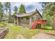 Charming home exterior with a red deck, set in a serene landscape with mature trees at 28065 Camel Heights Cir, Evergreen, CO 80439