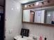 Small, dated bathroom with a tiled wall, mirror cabinet, and minimal decor at 7486 Patrick St, Fort Lupton, CO 80621
