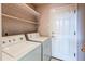 Functional laundry room with washer, dryer, shelving, and access to the outside at 12388 E Caspian Dr, Aurora, CO 80014