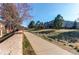 Concrete sidewalk on community grounds surrounded by mature trees and an office building at 12388 E Caspian Dr, Aurora, CO 80014