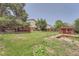 Sprawling fenced backyard featuring a deck, grass, mature trees, and a storage shed at 1824 S Granby St, Aurora, CO 80012