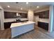 A spacious kitchen featuring dark cabinets, stainless steel appliances, and a large island with quartz countertops at 393 Grey Rock St, Brighton, CO 80601