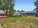 Backyard with a green lawn, wood deck, flowerbeds, and the exterior of the house, on a sunny day at 3750 S Galapago St, Englewood, CO 80110