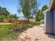 Lush backyard with roses, a stone patio, a shed, and a glimpse of the neighboring houses at 3750 S Galapago St, Englewood, CO 80110