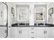 Bright bathroom featuring double sinks, sleek white cabinetry, modern fixtures, and illuminated vanity mirrors at 15353 E 98Th Pl, Commerce City, CO 80022