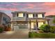 Charming two-story home featuring a brick facade, well-maintained lawn, and attached two-car garage at dusk at 15353 E 98Th Pl, Commerce City, CO 80022