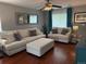 Inviting living room featuring a white sectional sofa, elegant blue curtains, ceiling fan and a large decorative mirror at 15353 E 98Th Pl, Commerce City, CO 80022