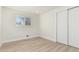 An empty bedroom with neutral paint and a light wood floor boasts a window and closet at 6699 S Pennsylvania St, Centennial, CO 80121