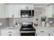 Close up of range wall featuring stone countertops, gray tile backsplash, and stainless steel microwave at 6699 S Pennsylvania St, Centennial, CO 80121