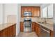 Kitchen area featuring stainless steel appliances, tile backsplash, and wooden cabinets at 1420 S Leyden St, Denver, CO 80224