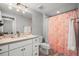 Well-lit bathroom with a large vanity, a pink patterned shower curtain, and tiled flooring at 4535 W 50Th Ave, Denver, CO 80212