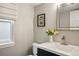 Well-lit half bathroom features a modern sink, decorative mirror, and a charming floral accent at 8140 S Storm King Peak, Littleton, CO 80127