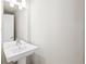 Modern half-bathroom with a pedestal sink, a mirror, and clean design elements at 1733 Irving St # 101, Denver, CO 80204