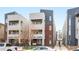Modern townhome showcasing brick and stucco exterior, with a grey roof, and a cozy porch swing at 1733 Irving St # 101, Denver, CO 80204