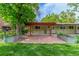 Charming backyard patio area with red pergola and surrounding greenery at 5890 W Quarles Dr, Littleton, CO 80128