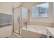Bathroom with tiled bathtub and a glass-enclosed shower, a window, and tile flooring at 10440 Olathe, Commerce City, CO 80022