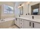 Bathroom featuring a double vanity with quartz countertops, black fixtures, a soaking tub, and tile floors at 10440 Olathe, Commerce City, CO 80022