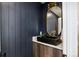 Stylish powder room featuring a modern vanity, black vessel sink and navy wood paneled walls at 4101 S Lincoln St, Englewood, CO 80113