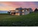 Stunning home exterior against a colorful sunset sky, highlighting the unique architectural design and lush greenery at 1764 Mesa Ridge Ln, Castle Rock, CO 80108