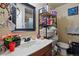View of a cluttered bathroom with a sink, mirror, shelving, and adjacent toilet at 12458 E Kansas Pl, Aurora, CO 80012