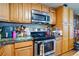 Well lit kitchen with wood cabinets, stainless steel oven and microwave at 12458 E Kansas Pl, Aurora, CO 80012