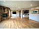 Open living room featuring hardwood floors, stone fireplace, bar, and recessed lighting at 15857 E Aberdeen Ave, Centennial, CO 80016