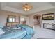 Spacious main bedroom suite with tray ceiling, a ceiling fan, adjacent room and a large TV at 15857 E Aberdeen Ave, Centennial, CO 80016