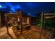 Covered flagstone patio area with a dining set, outdoor fireplace, and built-in grill at night at 15857 E Aberdeen Ave, Centennial, CO 80016