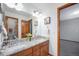 Bright bathroom featuring double sinks, granite countertops, wood cabinets, and a decorative mirror at 12518 W 77Th Pl, Arvada, CO 80005