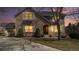 Attractive two-story stone home with inviting front entrance, evening lighting, and a well-maintained lawn at 12518 W 77Th Pl, Arvada, CO 80005