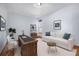 Bright living room with light blue walls, wooden desk and shelving unit, and a comfortable white couch near the window at 12518 W 77Th Pl, Arvada, CO 80005