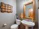 Charming powder room featuring a pedestal sink, stylish mirror, and decorative wall art at 12518 W 77Th Pl, Arvada, CO 80005
