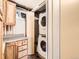 This area features a stacked washer and dryer in a closet adjacent to wooden cabinets and a window at 1856 S Steele St, Denver, CO 80210