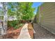 Landscaped backyard featuring mature trees, gravel, mulch, and a concrete walkway at 2205 Santa Fe Dr, Longmont, CO 80504