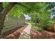 Landscaped backyard featuring mature trees, lush shrubs, and a concrete walkway at 2205 Santa Fe Dr, Longmont, CO 80504
