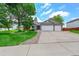 Charming home featuring a manicured lawn, mature trees, and a three-car garage with stone accents at 2205 Santa Fe Dr, Longmont, CO 80504